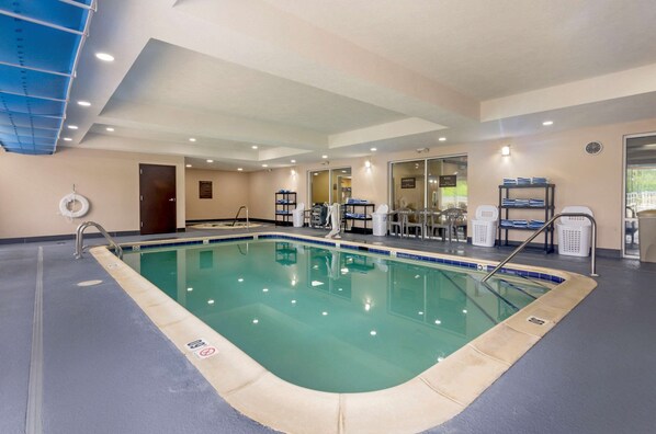 An indoor swimming pool with clear water, surrounded by a blue and beige tiled floor, and equipped with a ladder and a lifebuoy. - Comfort Inn & Suites Hillsville I-77 (Hillsville)