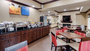 A buffet area with a variety of food items, a microwave, and a refrigerator. There are multiple tables and chairs arranged for dining. - Comfort Inn & Suites Hillsville I-77 (Hillsville)