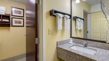 A bathroom with a granite sink, a mirror, and towels hanging on a rack.