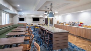A modern restaurant with a long counter, bar stools, and a green cushioned seating area. - Fairfield Inn & Suites Memphis I-240 & Perkins (Memphis)