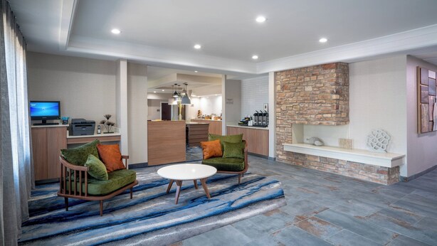 A modern living room with a stone fireplace, a dining area, and a kitchen. - Fairfield Inn & Suites Memphis I-240 & Perkins (Memphis)