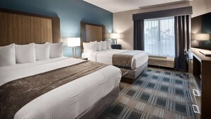 A hotel room with two beds, a large window with curtains, a desk with a flat-screen TV, and a heater. - Best Western Town Center Inn (Weslaco)