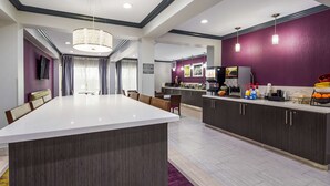 A modern kitchen with a central island, dark cabinetry, and a purple accent wall. - Best Western Town Center Inn (Weslaco)
