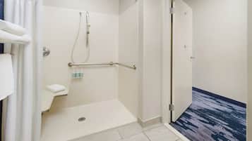 A modern bathroom with a walk-in shower, grab bars, and a white sink.