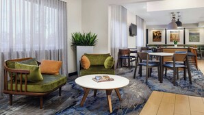 A hotel lobby with a green sofa, a round white table, and a dining area with chairs and a table. - Fairfield Inn by Marriott Philadelphia Airport (Philadelphia)