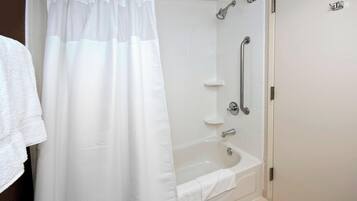 A modern bathroom with a glass shower enclosure, a bathtub, and a handrail.