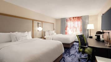 Une chambre d’hôtel avec deux lits, un bureau, une chaise, une télévision et une fenêtre avec des rideaux.