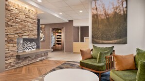 A lobby with a stone wall, a reception desk, a green sofa with cushions, and a white coffee table.