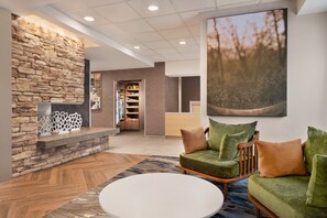 A lobby with a stone wall, a reception desk, a green sofa with cushions, and a white coffee table.