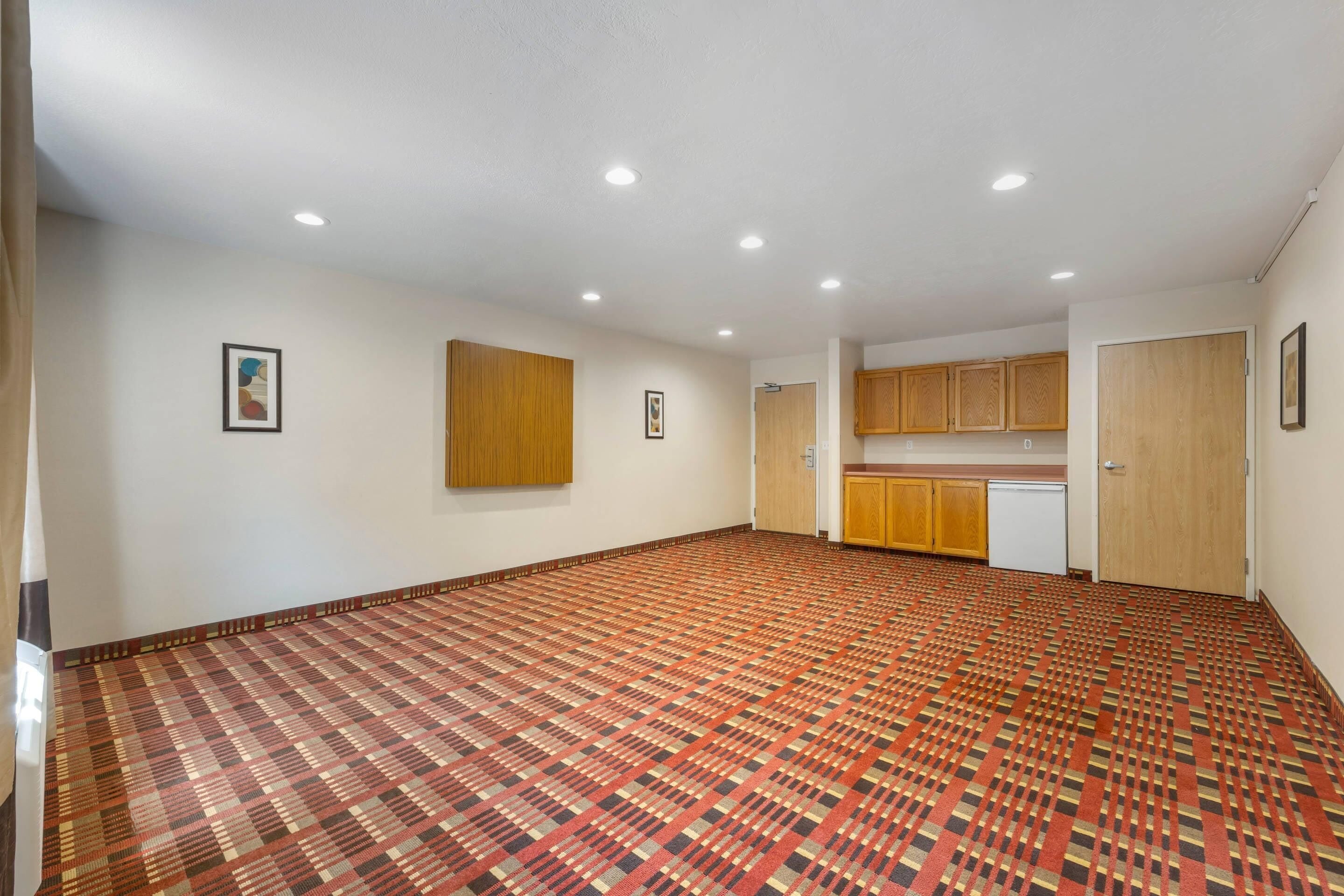 Quarto espaçoso com carpete estampado, armários de madeira e iluminação embutida no teto.