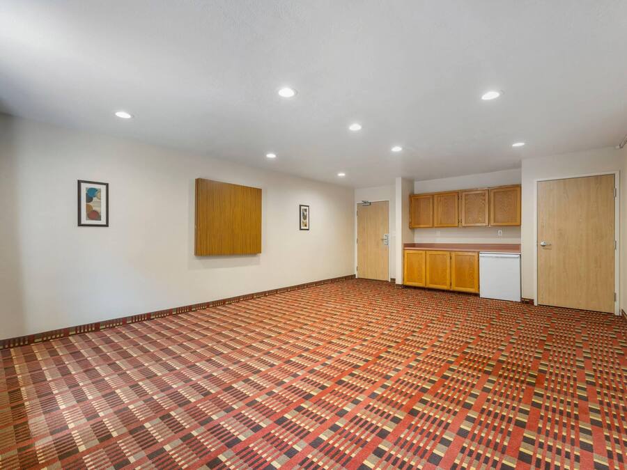 Una habitación amplia con alfombra estampada, armarios de madera y luces empotradas en el techo.