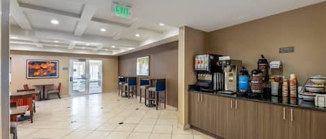 Un vestíbulo de hotel con una estación de café, zona de estar y señal de salida.
