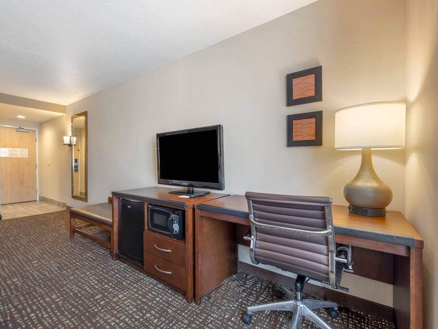 Habitación de hotel con escritorio, televisión, lámpara y microondas.