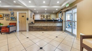A reception area with a counter, a chair, a potted plant, and a glass door leading outside. - Comfort Inn & Suites Orem - Provo (Orem)