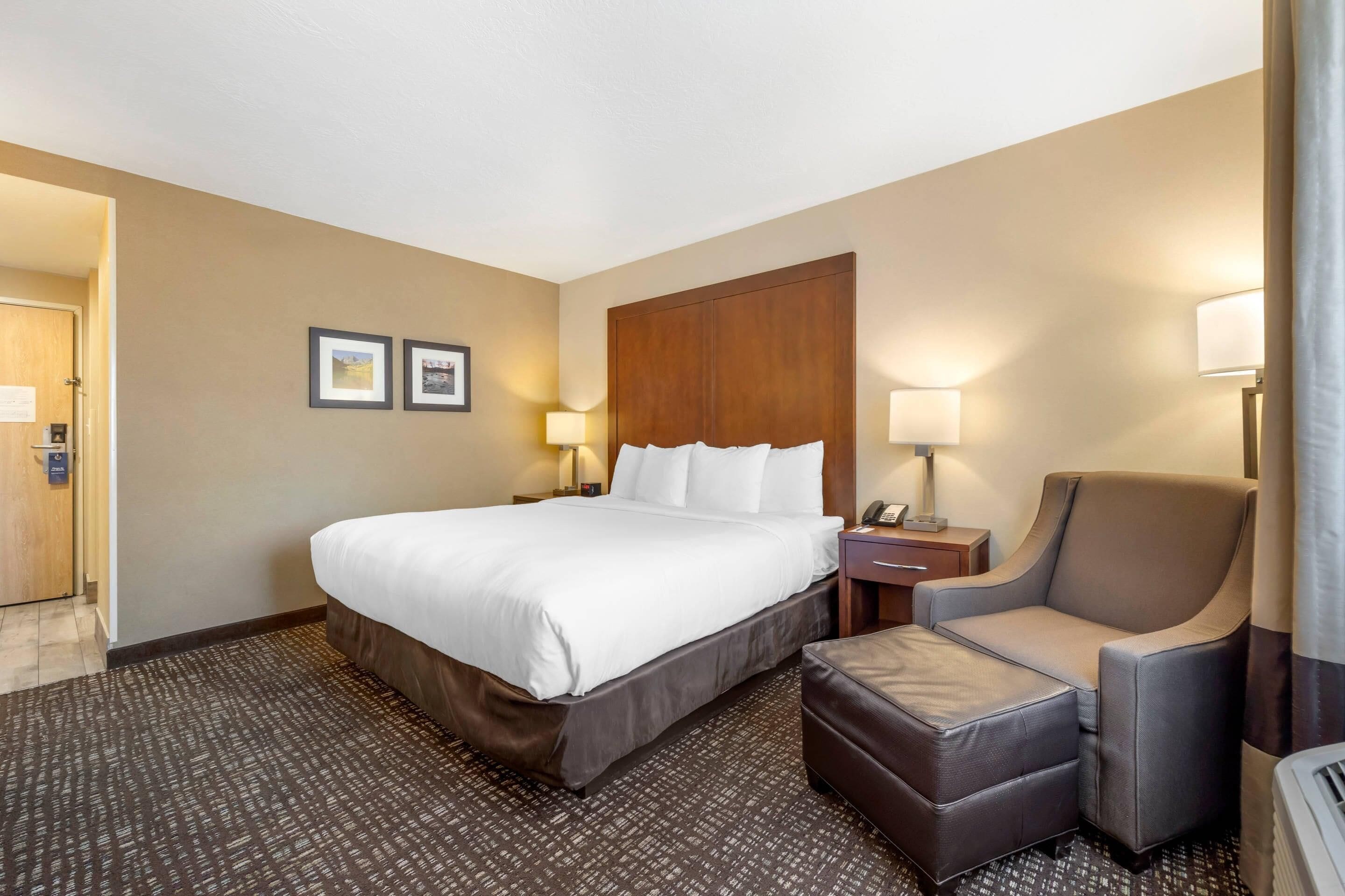 Una habitación de hotel con una cama grande, una silla, un escritorio y una lámpara.