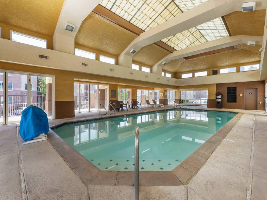 Una piscina interior con techo alto, ventanas grandes y zona cubierta.