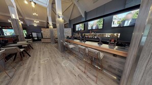 Un espace bar moderne doté d’un long comptoir, de plusieurs robinets et d’un coin salon avec des tabourets de bar.