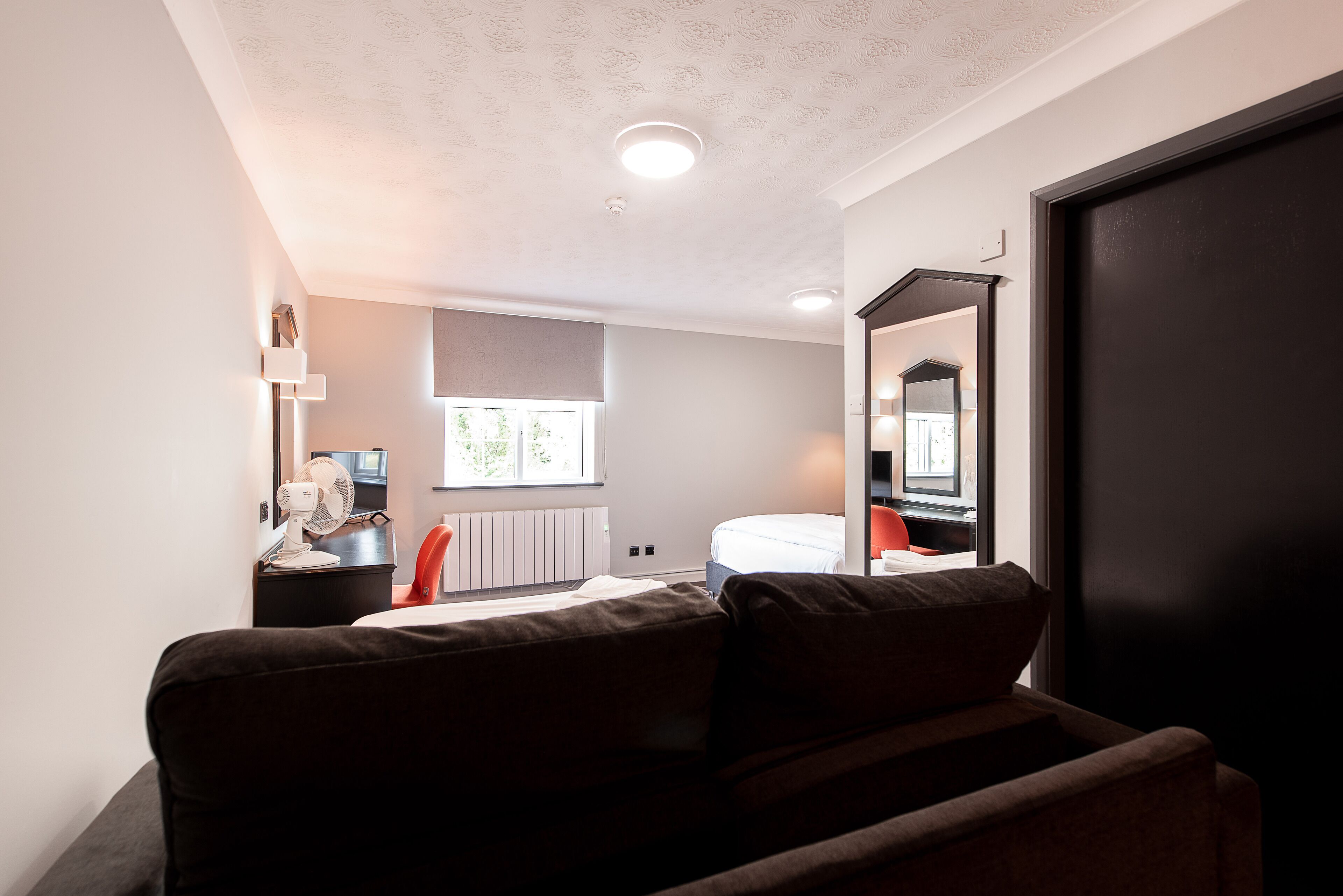 Una camera da letto moderna con un letto, un comodino e un grande specchio.