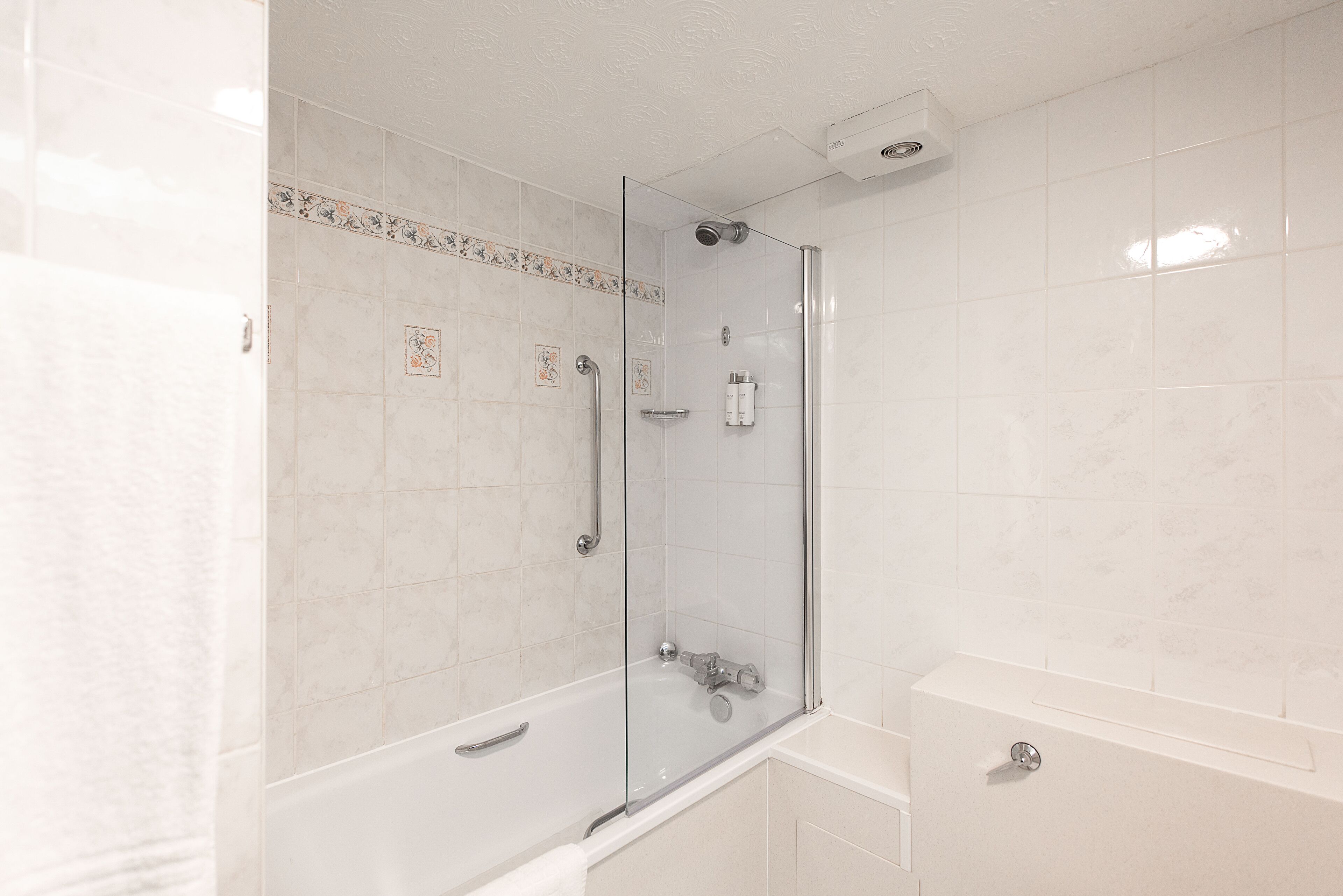 A modern bathroom with a glass-enclosed shower, a white bathtub, and a tiled shower area.