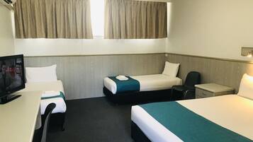 Habitación de hotel con dos camas individuales, un escritorio con silla, televisión y ventana con cortinas.