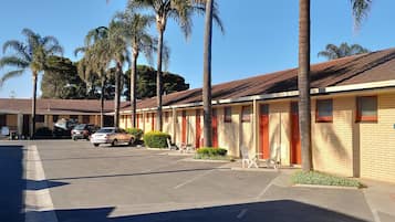 A motel with multiple rooms, a parking lot, and palm trees.