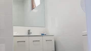 A bathroom with white cabinets, a mirror, and a toilet.