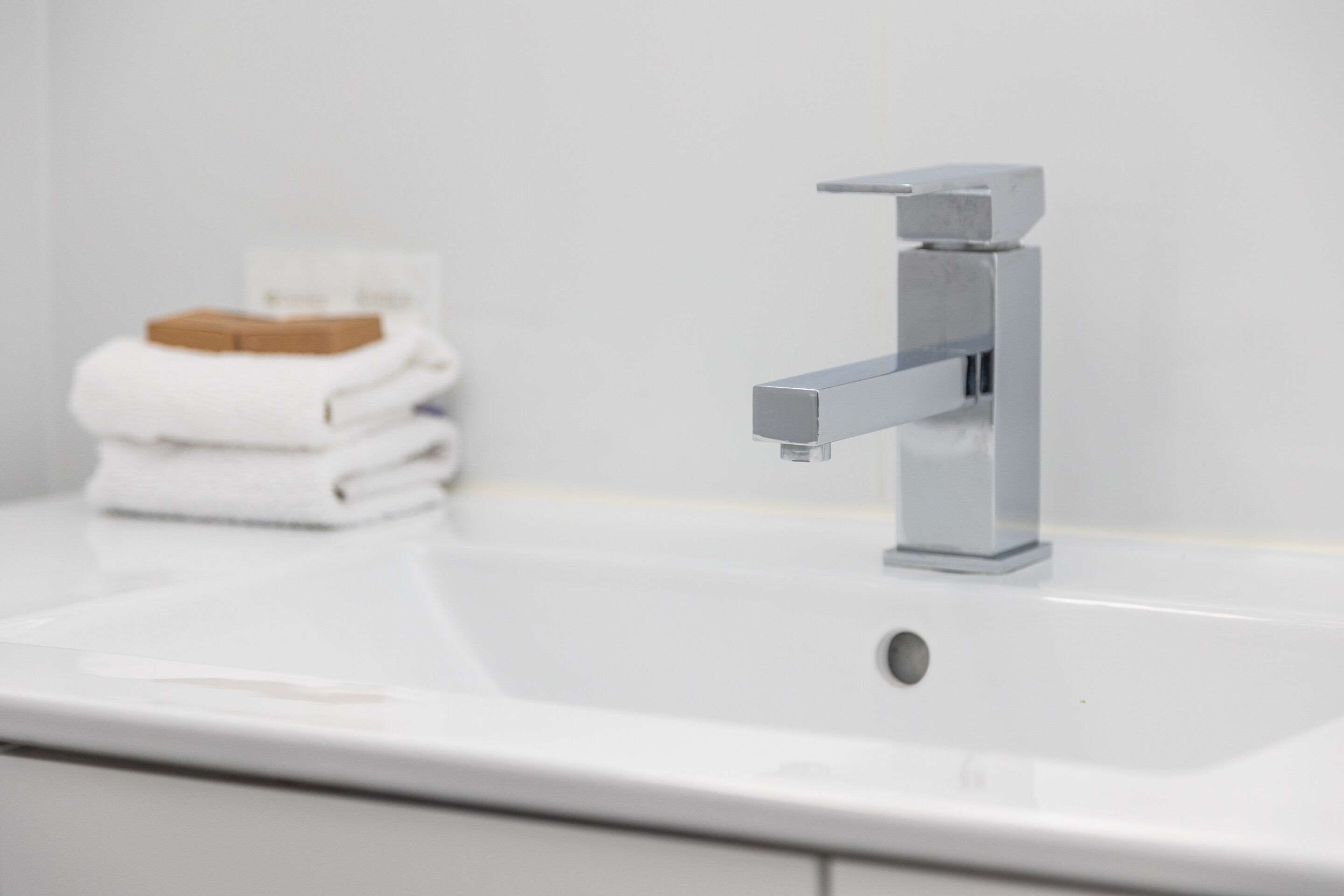 A bathroom sink with a modern faucet and a towel stack.