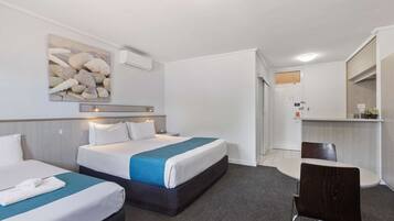 A hotel room with two beds, a desk, a chair, a large mirror, and a wall-mounted artwork of seashells.