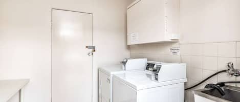 A laundry room with a washing machine, a dryer, and a sink.