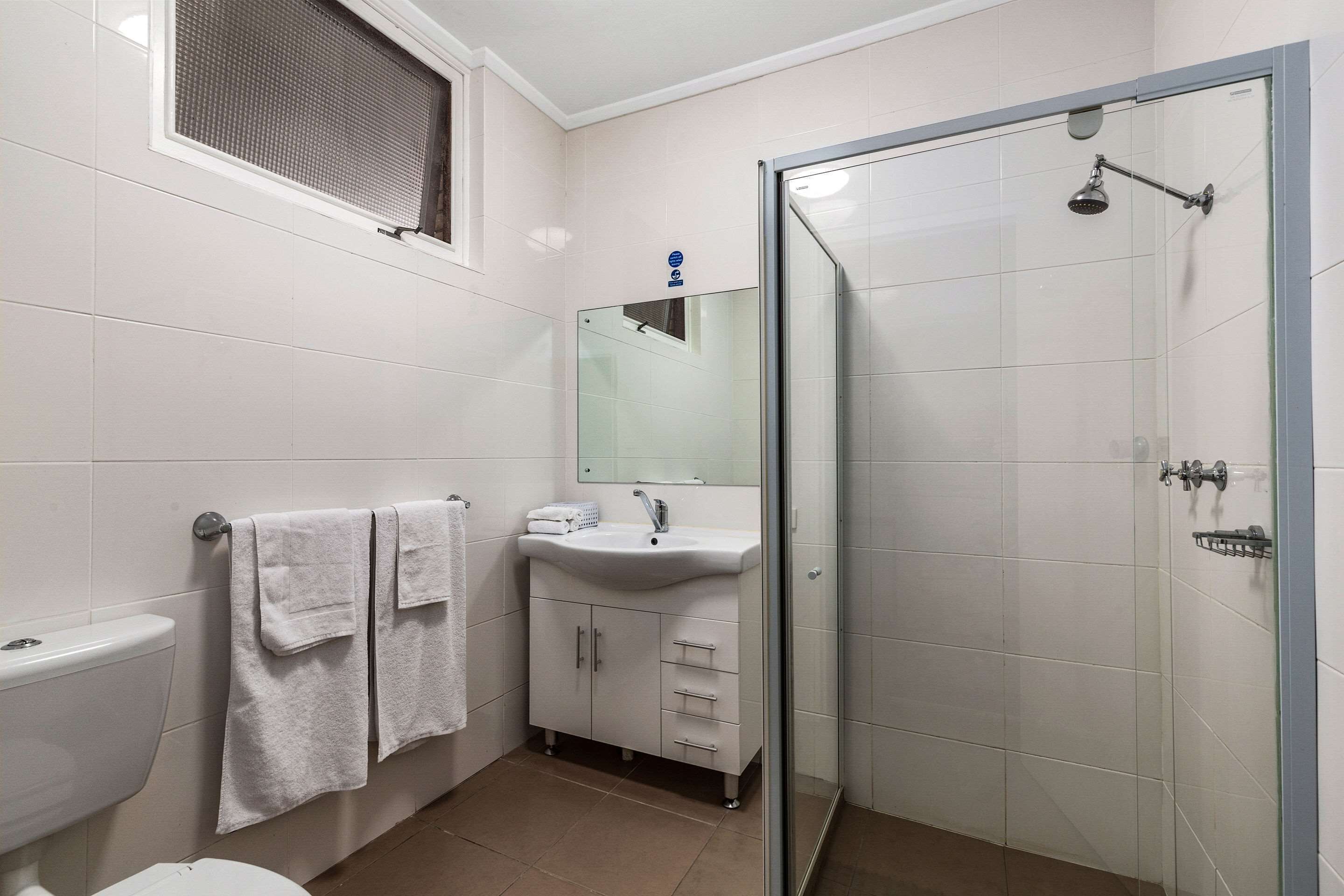 Ein modernes Badezimmer mit Toilette, Waschbecken und einer Duschkabine aus Glas.
