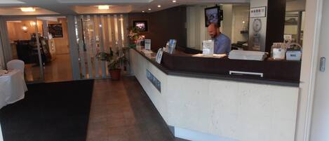 A reception area with a counter, a television, a clock, and a sign indicating the price of $55.00.