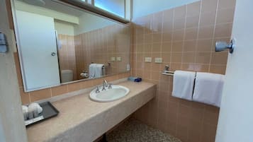 A bathroom with a sink, mirror, towel rack, and patterned floor tiles.