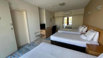 A hotel room with two beds, a desk, a chair, and a television.