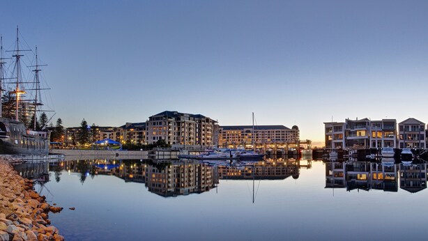A marina with boats, a large building with multiple balconies, and a dock with a ship named "BUFFALO". - Haven Marina Motel (Glenelg North)