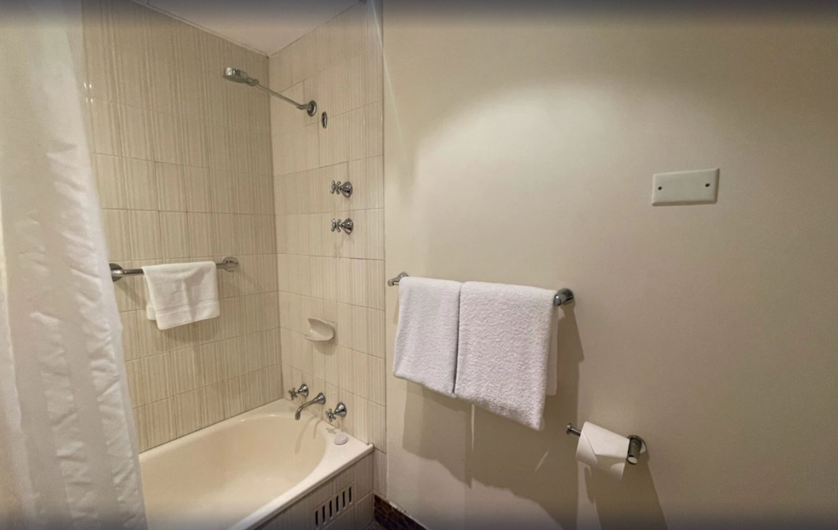 A bathroom with a bathtub, a shower, and two towel racks with towels.
