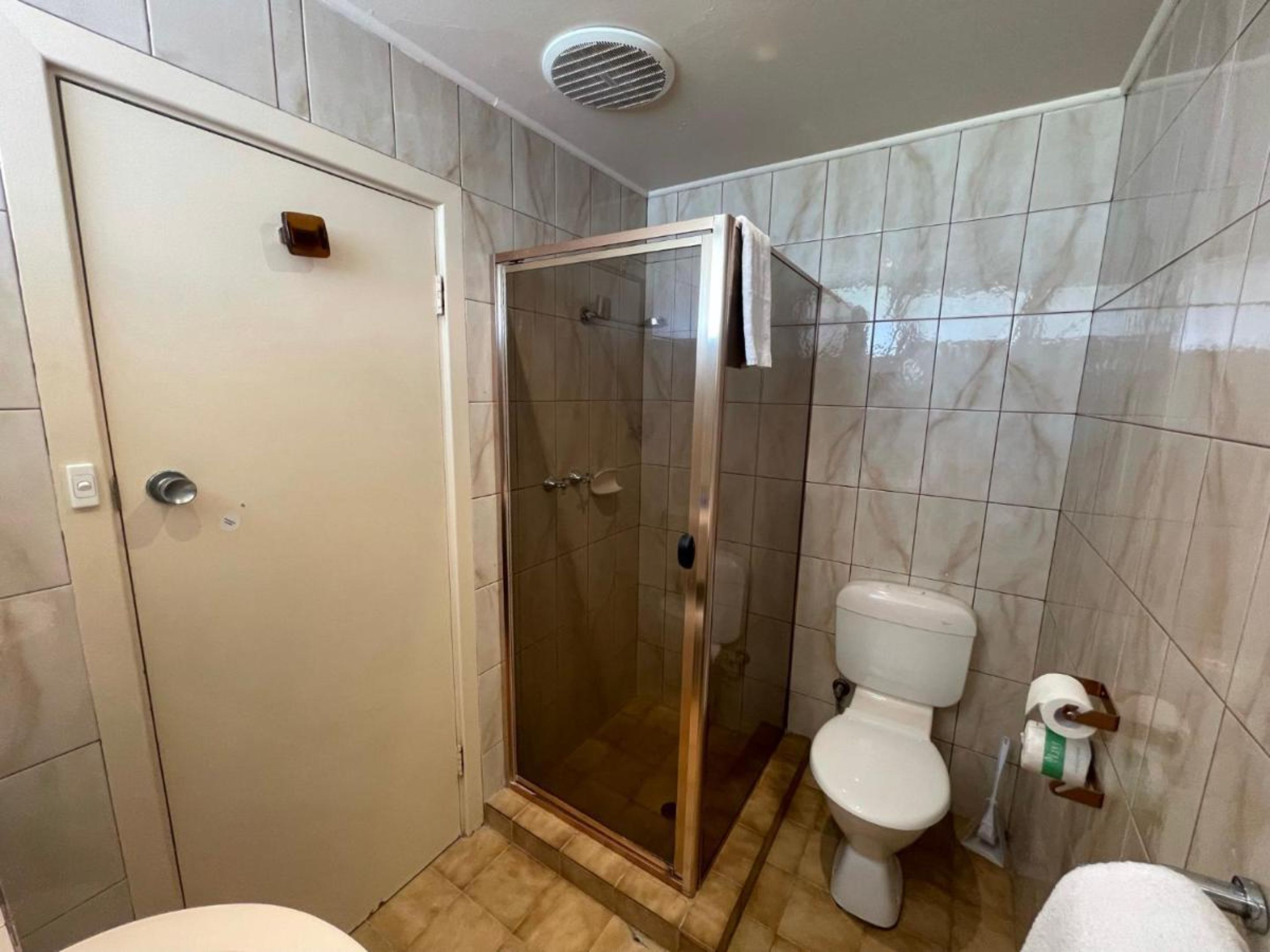 Un baño con cabina de ducha, inodoro y una puerta blanca.