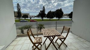 A balcony with a view of a marina, a road, and buildings in the distance. - Haven Marina Motel (Glenelg North)