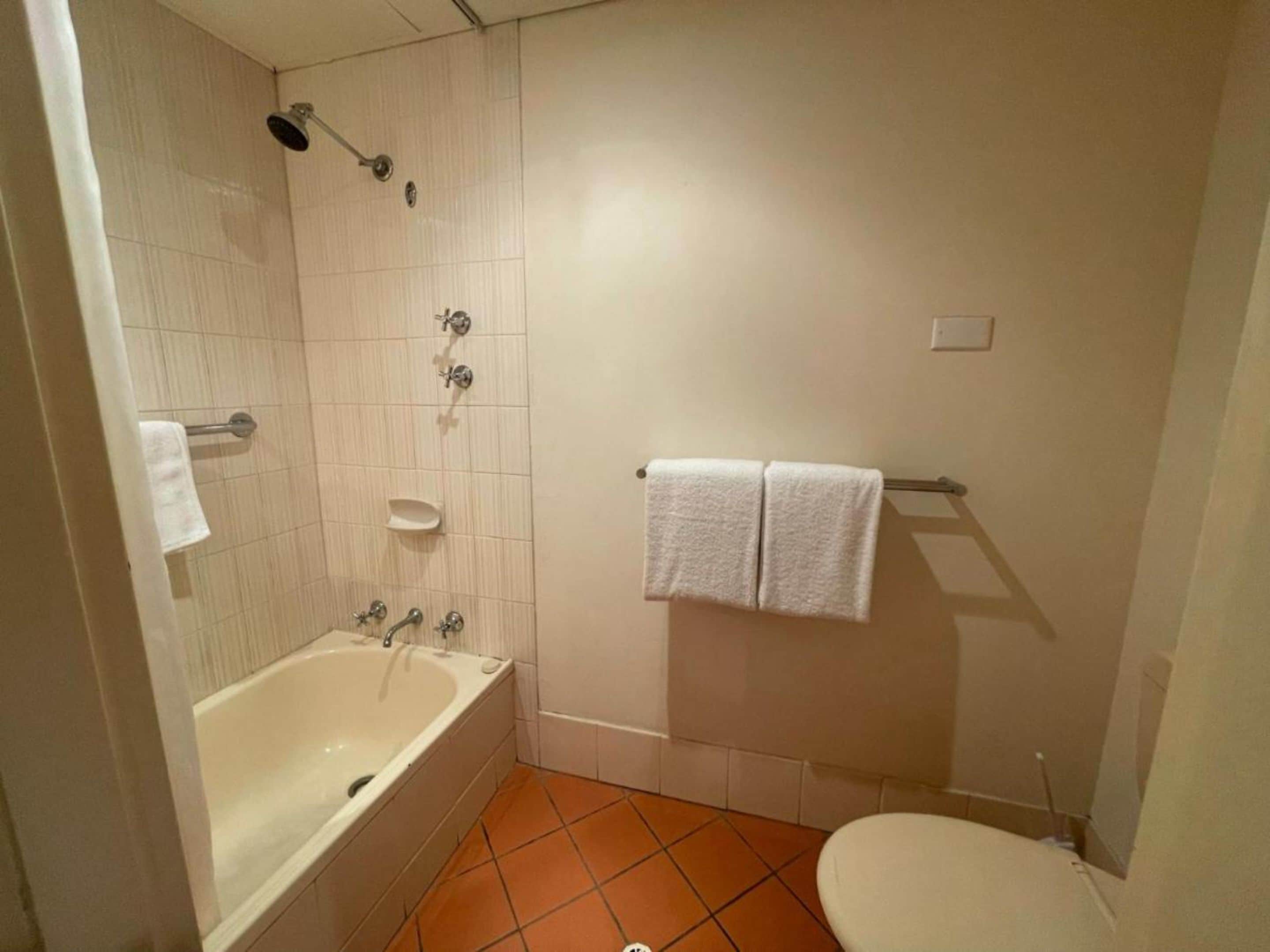 A bathroom with a bathtub, toilet, and a towel rack.