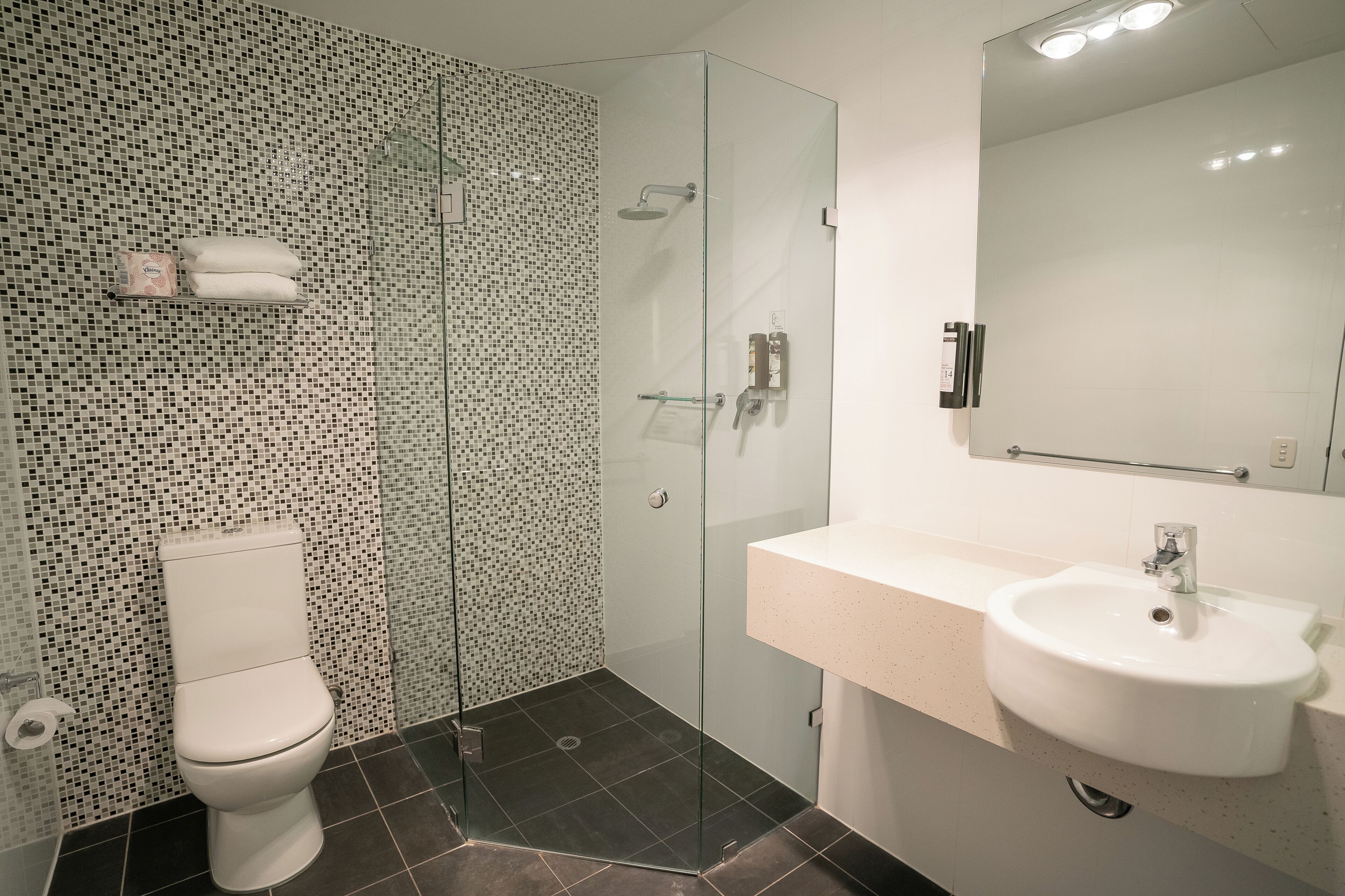 A modern bathroom with a glass-enclosed shower, a white sink, and a toilet.