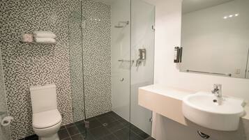 A modern bathroom with a glass-enclosed shower, a white sink, and a toilet.