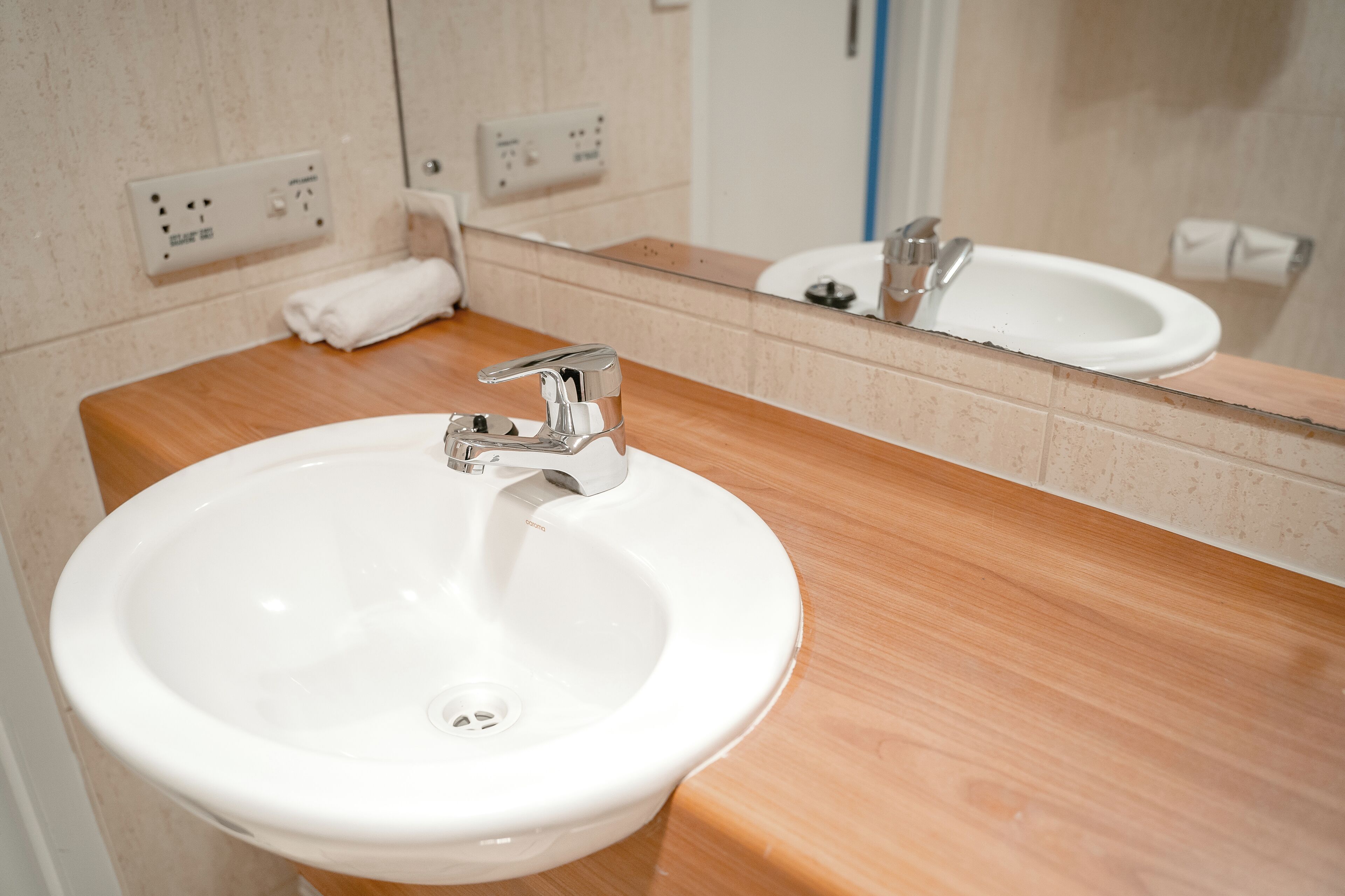 Un baño con un lavabo blanco, una encimera de madera y un espejo que refleja el lavabo y un inodoro.