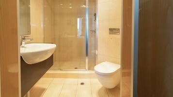Un baño moderno con ducha envuelta en vidrio, un lavamanos y un inodoro.