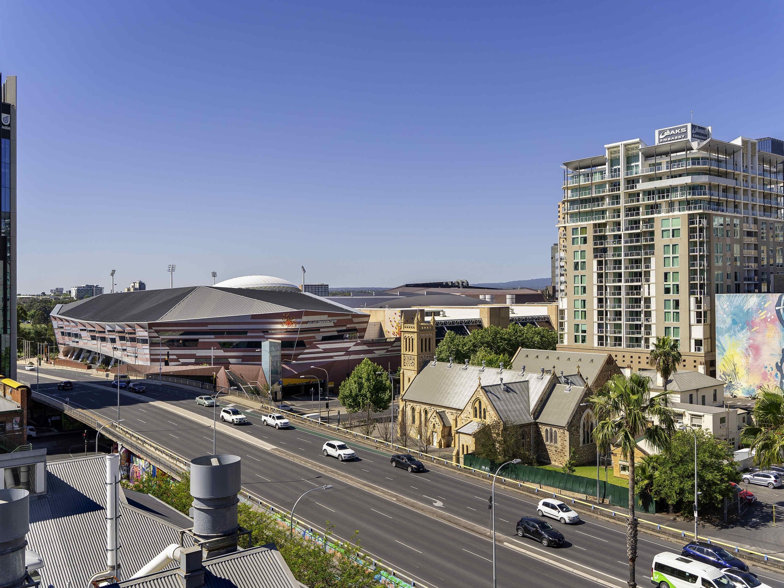 A modern building with a unique angular design, a large dome structure, and a multi-story hotel with balconies.