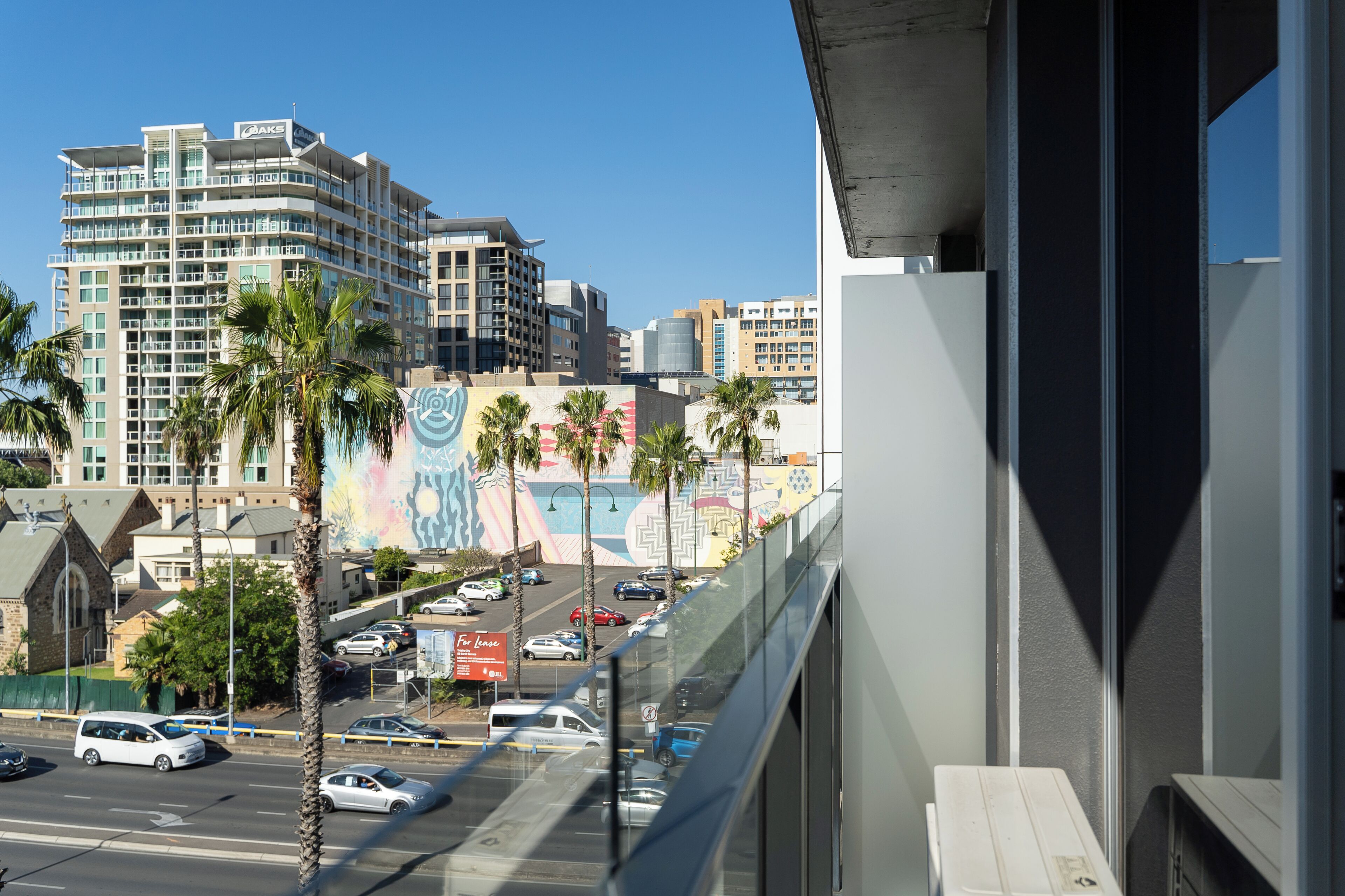 A hotel with a view of a busy street and palm trees.