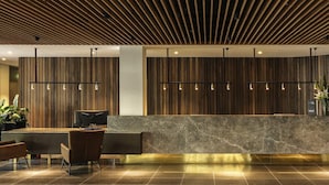 Un área de recepción con techo de listones de madera, mostrador de mármol y una zona de estar con sillones.