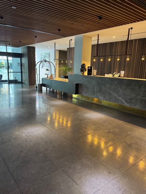 A modern reception area with a marble counter, a potted plant, and a reception desk. - Adelaide Rockford (Adelaide)