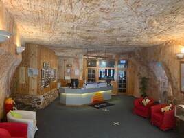 Zona de recepción con interior de madera, mostrador de recepción y asientos rojos.