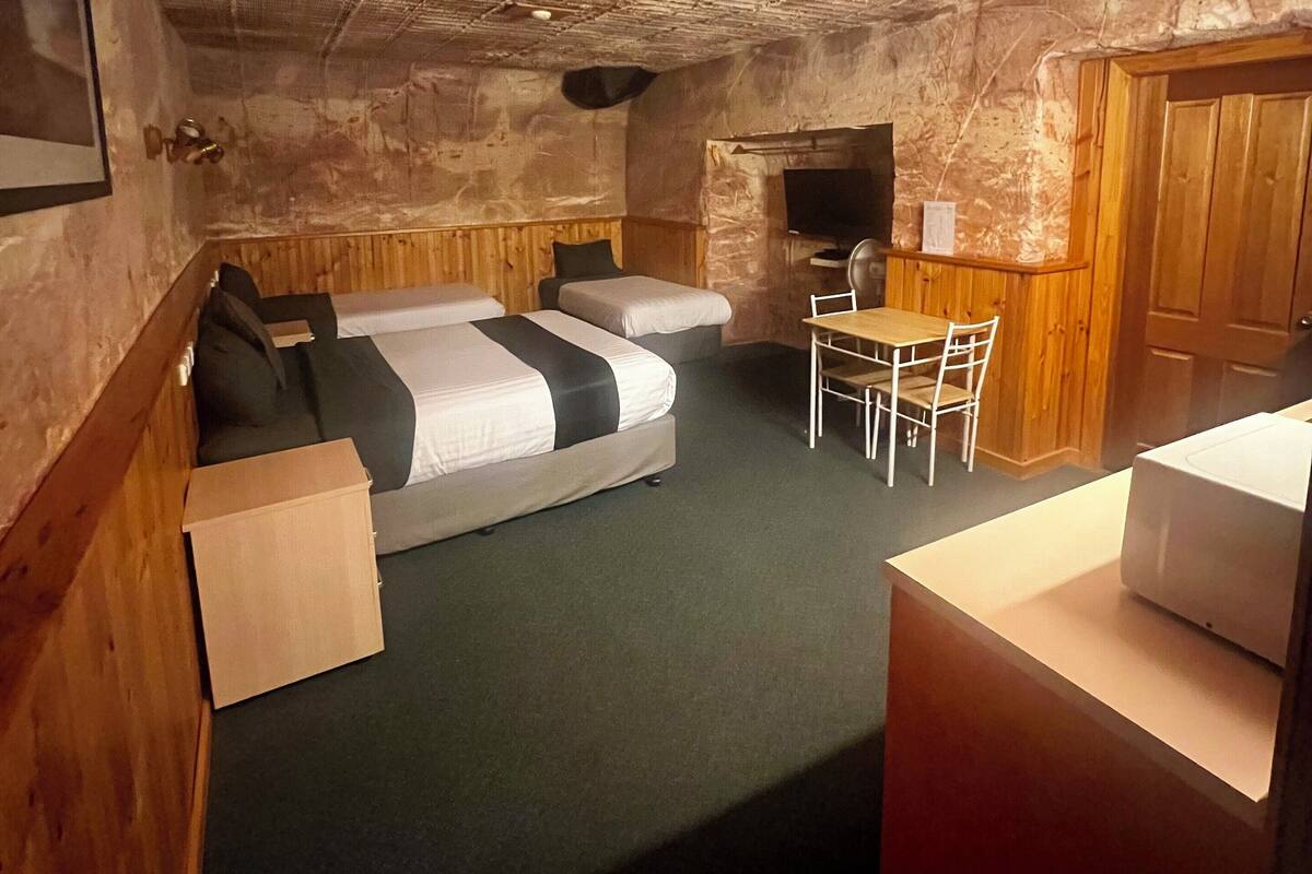 A compact room with a bunk bed, a small table with chairs, a microwave, and a television.