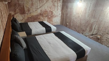 Una habitación con dos camas, cada una con ropa de cama blanco y negro, cabeceros de madera y una pequeña mesa entre ellas.