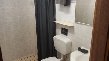 Un baño con inodoro, lavamanos y zona de ducha.